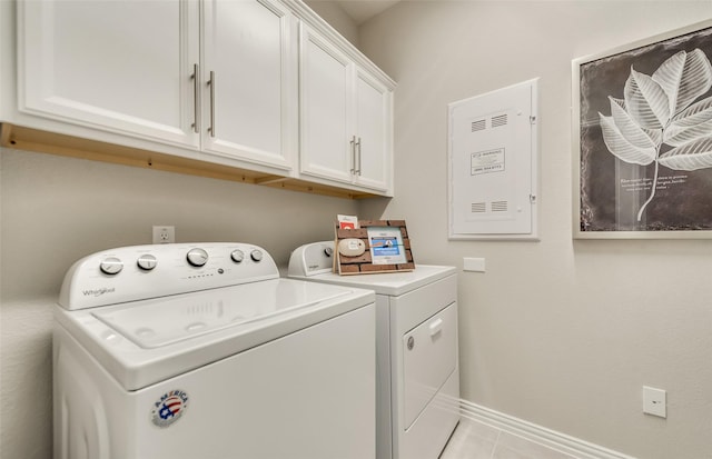 laundry area with light tile patterned flooring, washing machine and clothes dryer, and cabinets