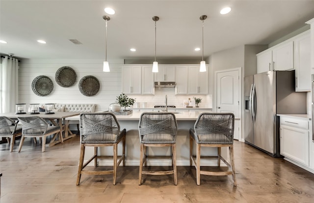 kitchen with white cabinets, hanging light fixtures, and stainless steel fridge