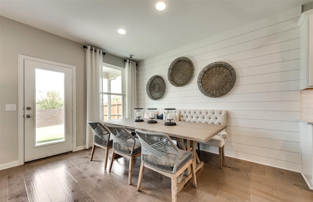 dining area with light wood-type flooring, wood walls, and breakfast area