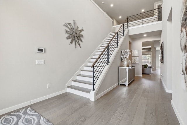 stairway with hardwood / wood-style flooring and a high ceiling