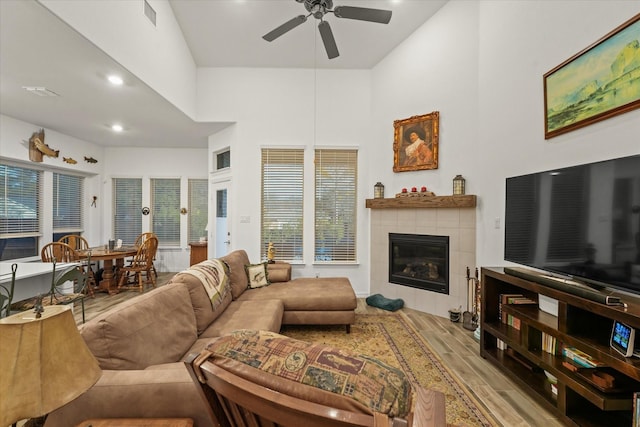 living room featuring ceiling fan and a tiled fireplace