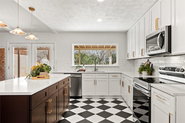 kitchen with dark brown cabinetry, white cabinets, appliances with stainless steel finishes, and pendant lighting