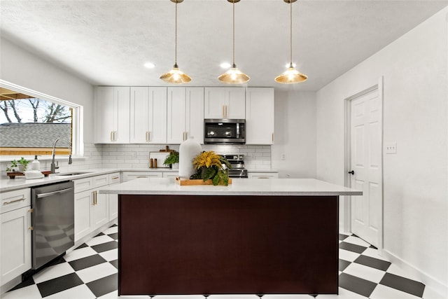 kitchen featuring stainless steel appliances, pendant lighting, white cabinets, and a center island