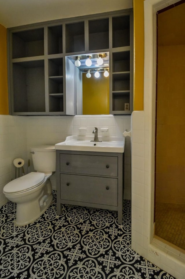 bathroom featuring toilet, a tile shower, tile walls, tile patterned floors, and vanity