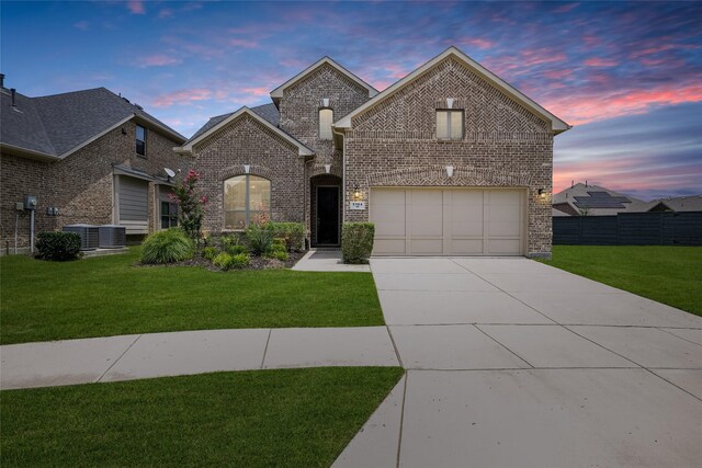 french country inspired facade with central AC unit, a yard, and a garage