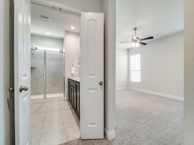 bathroom with ceiling fan, tile patterned flooring, tiled shower, and vanity