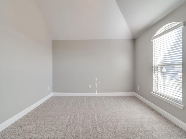 carpeted empty room with vaulted ceiling