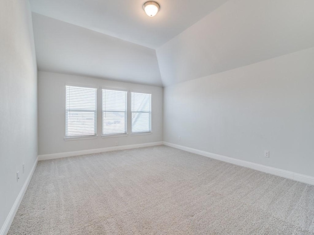 carpeted spare room with vaulted ceiling and plenty of natural light