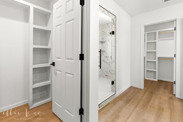 bathroom featuring wood-type flooring and an enclosed shower