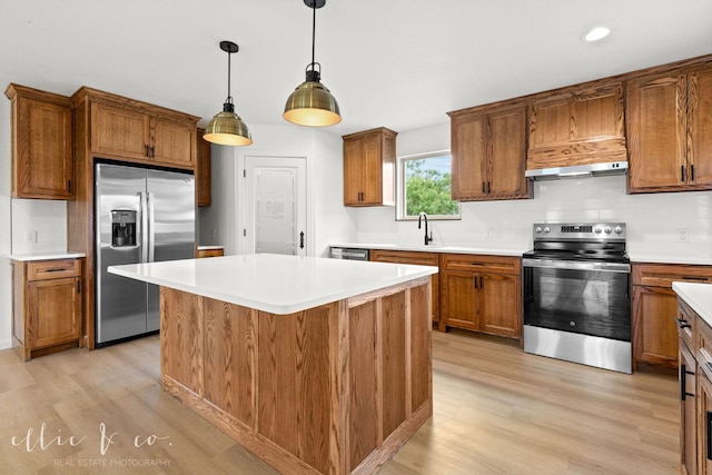 kitchen with tasteful backsplash, light wood-type flooring, appliances with stainless steel finishes, and hanging light fixtures