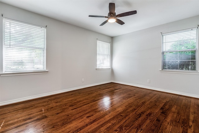 empty room featuring ceiling fan, a healthy amount of sunlight, and dark hardwood / wood-style flooring