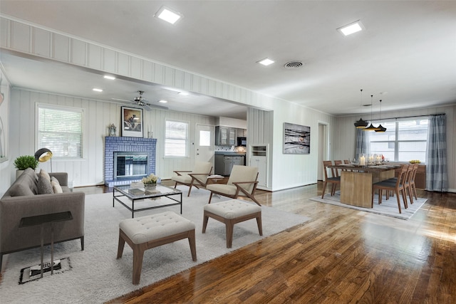 living room featuring ceiling fan, a healthy amount of sunlight, a fireplace, and hardwood / wood-style floors