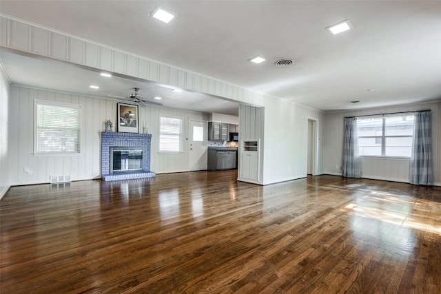 unfurnished living room with ceiling fan, dark hardwood / wood-style floors, and a brick fireplace