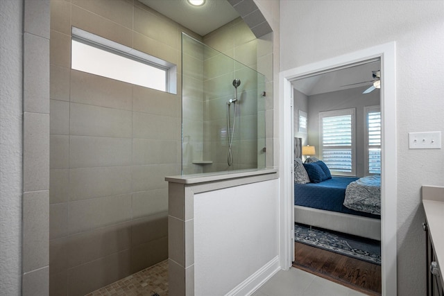 bathroom featuring ceiling fan, vanity, tile patterned flooring, and tiled shower