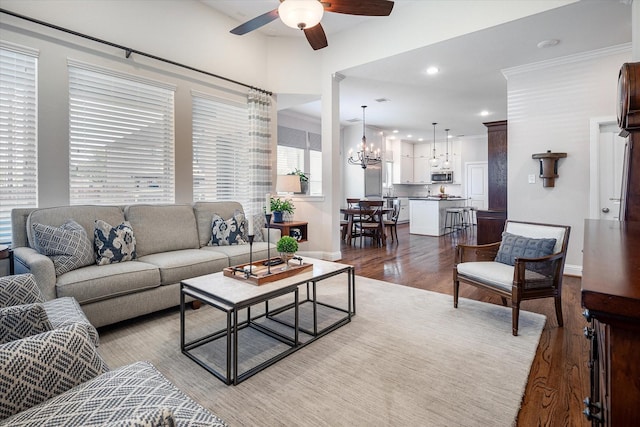 living room featuring ceiling fan with notable chandelier, light hardwood / wood-style floors, and ornamental molding