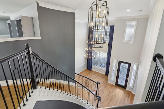 entrance foyer featuring an inviting chandelier, hardwood / wood-style floors, and crown molding