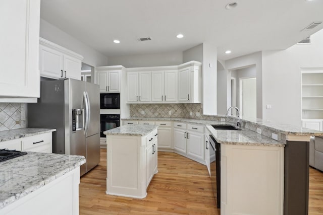 kitchen featuring white cabinetry, a center island, sink, and black appliances