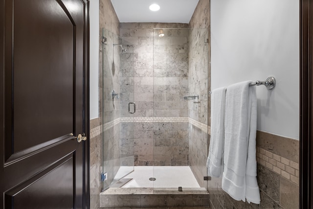 bathroom featuring a shower with shower door and tile walls