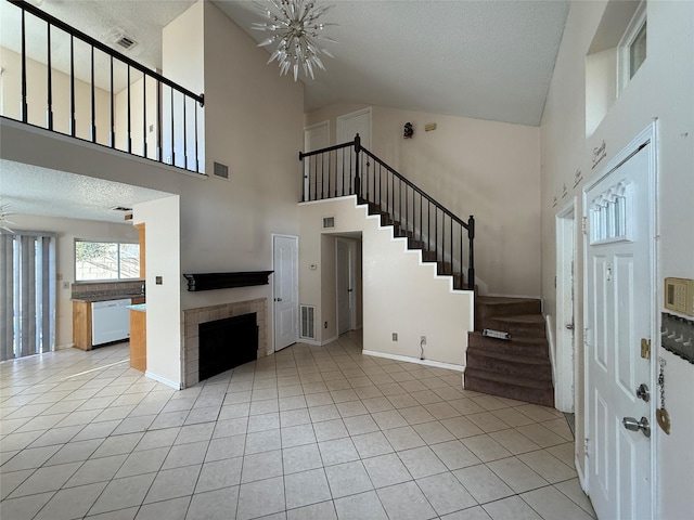 interior space featuring a tiled fireplace, light tile patterned floors, a chandelier, and a high ceiling