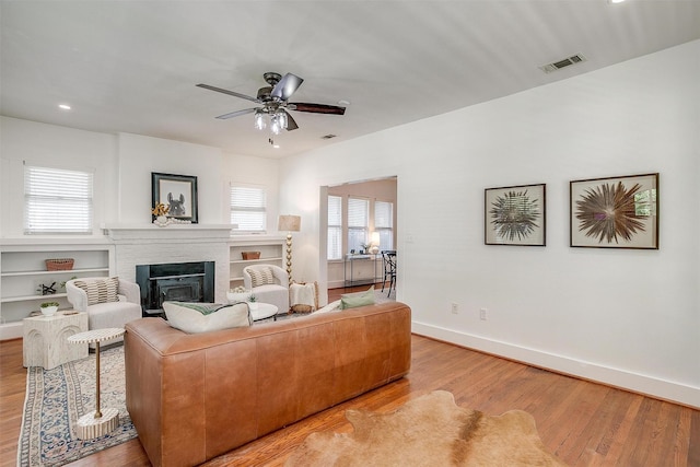 living room with ceiling fan, light wood-type flooring, and a healthy amount of sunlight