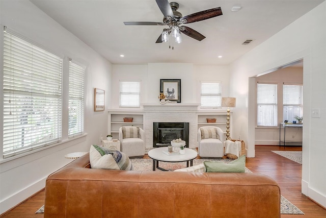 living room with hardwood / wood-style flooring, a brick fireplace, and ceiling fan