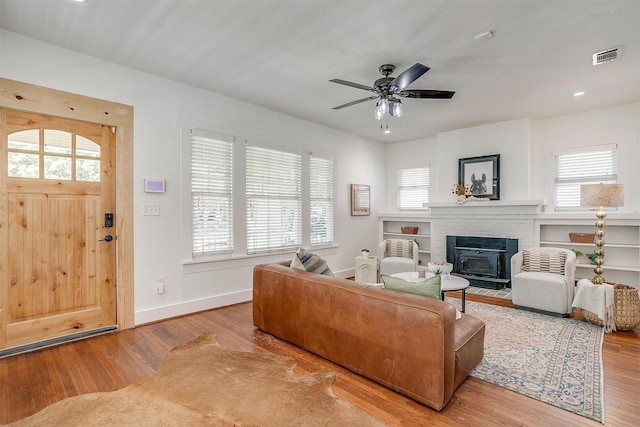 living room with ceiling fan, a healthy amount of sunlight, a fireplace, and light hardwood / wood-style floors