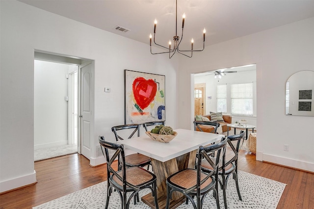 dining room featuring ceiling fan with notable chandelier and hardwood / wood-style flooring