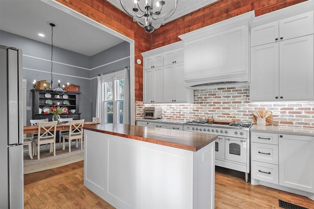 kitchen with appliances with stainless steel finishes, an inviting chandelier, white cabinetry, and decorative light fixtures