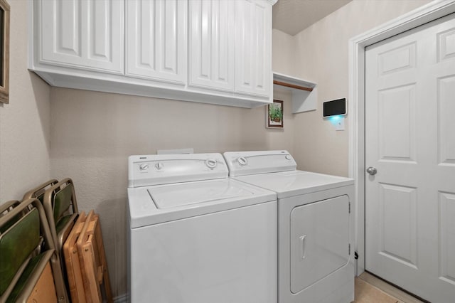 clothes washing area with cabinets and washer and clothes dryer