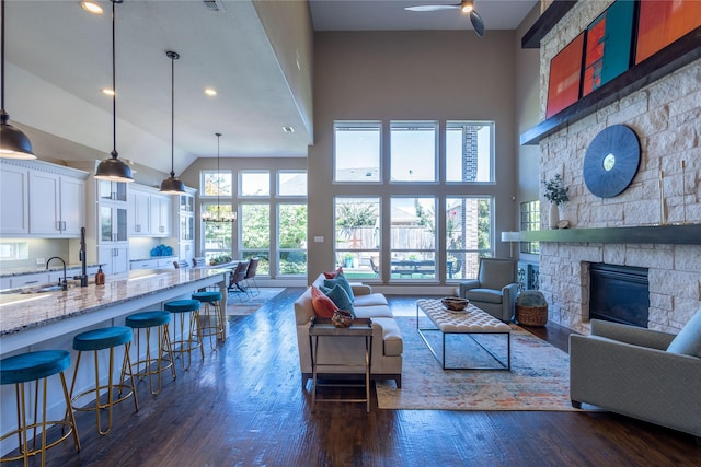 living room featuring high vaulted ceiling, sink, dark hardwood / wood-style floors, and a fireplace