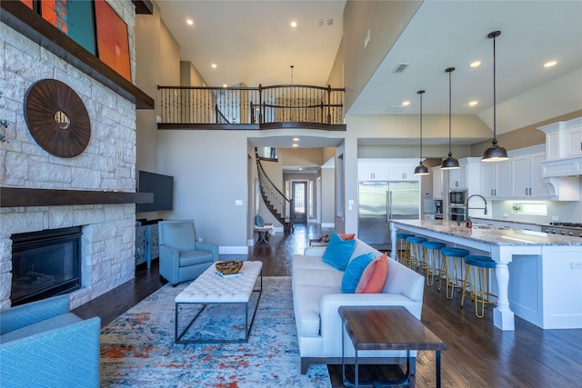 living room featuring sink, a fireplace, dark hardwood / wood-style flooring, and a high ceiling