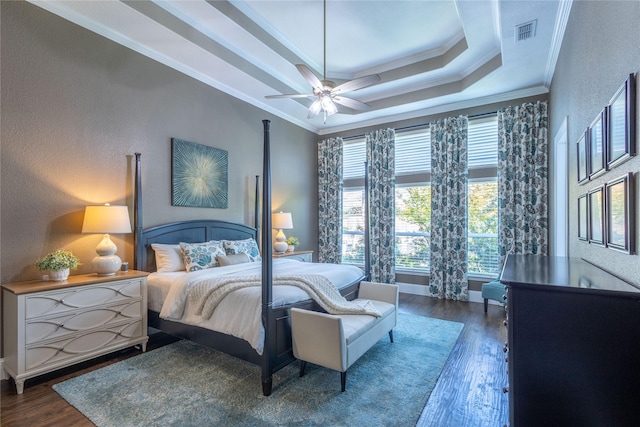 bedroom featuring ceiling fan, dark wood-type flooring, crown molding, and a tray ceiling