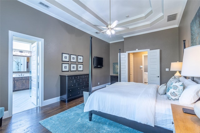 bedroom with dark hardwood / wood-style floors, a raised ceiling, ceiling fan, ensuite bathroom, and crown molding