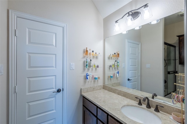 bathroom with lofted ceiling, vanity, and a shower with door