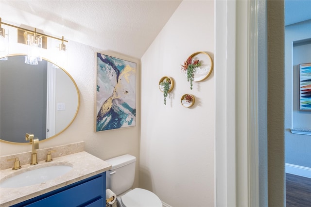 bathroom with toilet, a textured ceiling, vaulted ceiling, and vanity