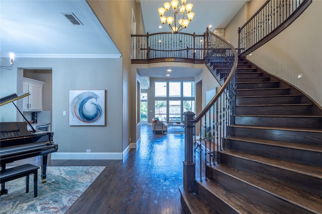 entryway with a notable chandelier, dark hardwood / wood-style flooring, crown molding, and a towering ceiling