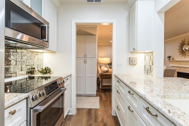 kitchen featuring appliances with stainless steel finishes, dark hardwood / wood-style floors, crown molding, white cabinets, and light stone counters