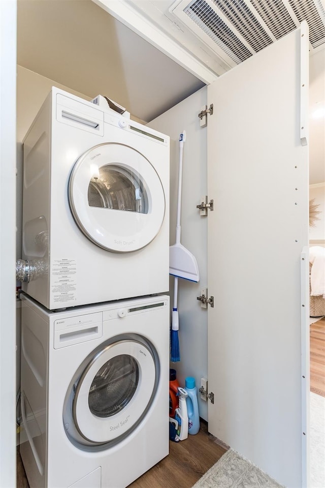 laundry area featuring hardwood / wood-style floors and stacked washer and dryer