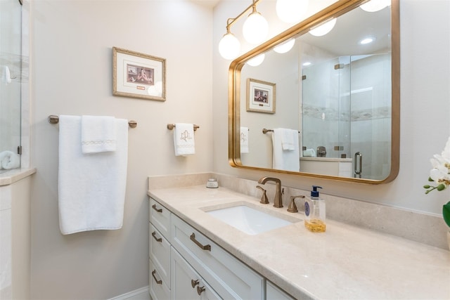 bathroom featuring a shower with shower door and vanity