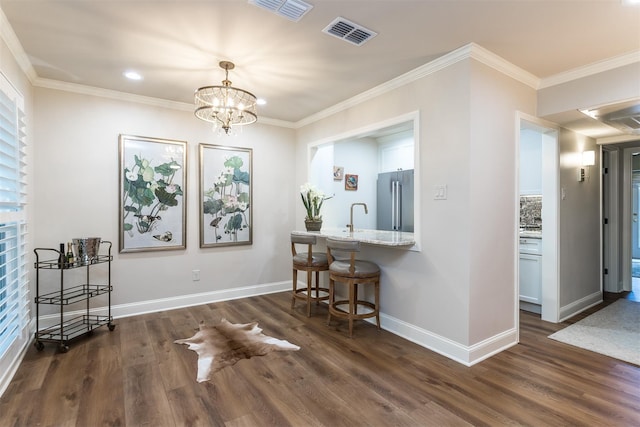 dining space with dark wood-type flooring, ornamental molding, and a notable chandelier