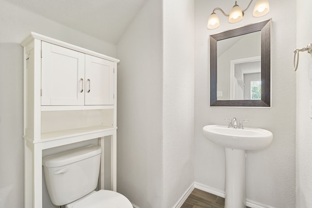 bathroom featuring toilet, vaulted ceiling, wood-type flooring, and sink