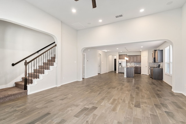 unfurnished living room with ceiling fan and dark wood-type flooring