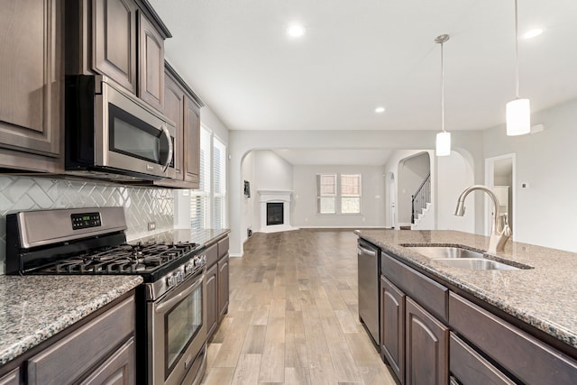 kitchen featuring hanging light fixtures, stainless steel appliances, dark brown cabinetry, and sink