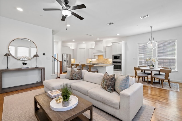 living room with ceiling fan, sink, and light hardwood / wood-style flooring