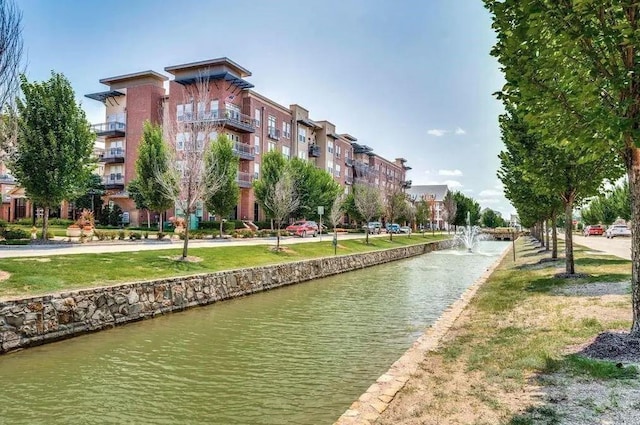 view of property's community with a water view and a lawn