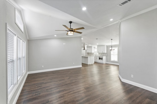 unfurnished living room with lofted ceiling, dark wood-type flooring, ceiling fan with notable chandelier, and ornamental molding