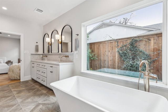 bathroom with tasteful backsplash, a healthy amount of sunlight, vanity, and a washtub