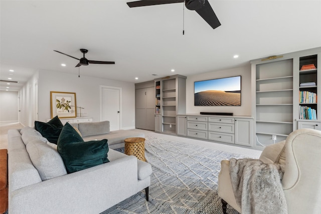 living room with ceiling fan, light colored carpet, and built in features