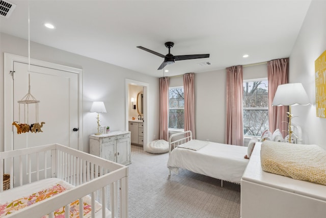 bedroom featuring ceiling fan, light carpet, and ensuite bath