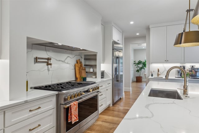 kitchen with white cabinets, tasteful backsplash, sink, light stone counters, and high quality appliances